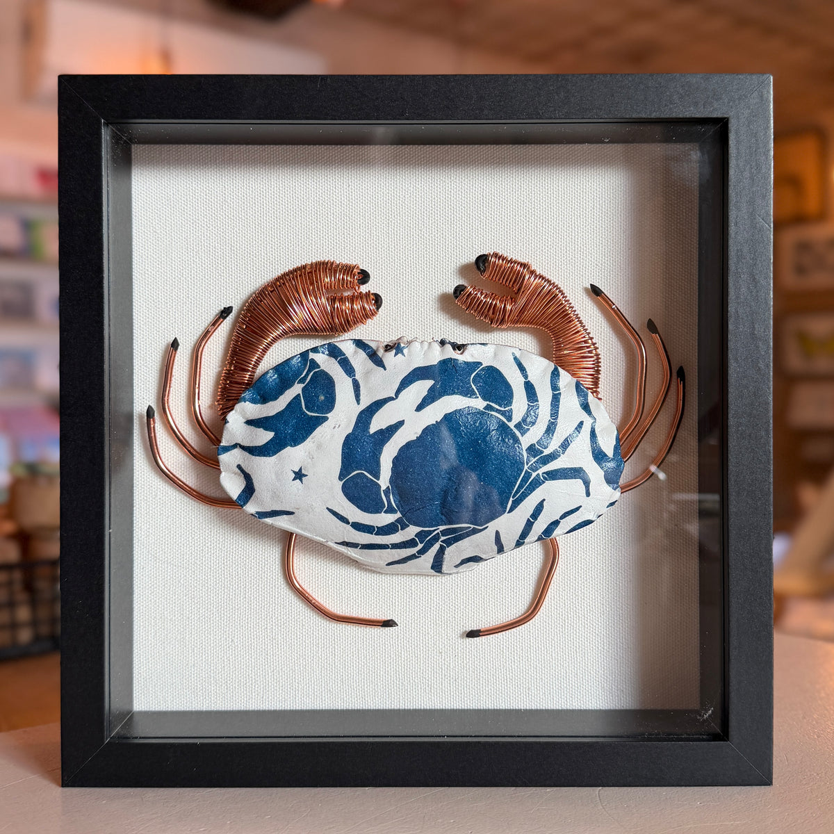 Decoupaged Cromer Crab shell with copper wire legs in shadow mount frame.